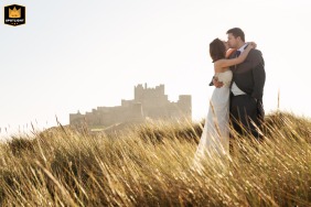At Bamburgh Castle, the bride and groom stand together, the majestic castle providing a breathtaking backdrop to their special moment.